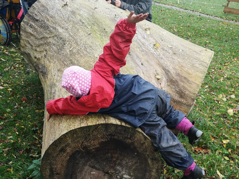 Kind spielt auf Holzstamm